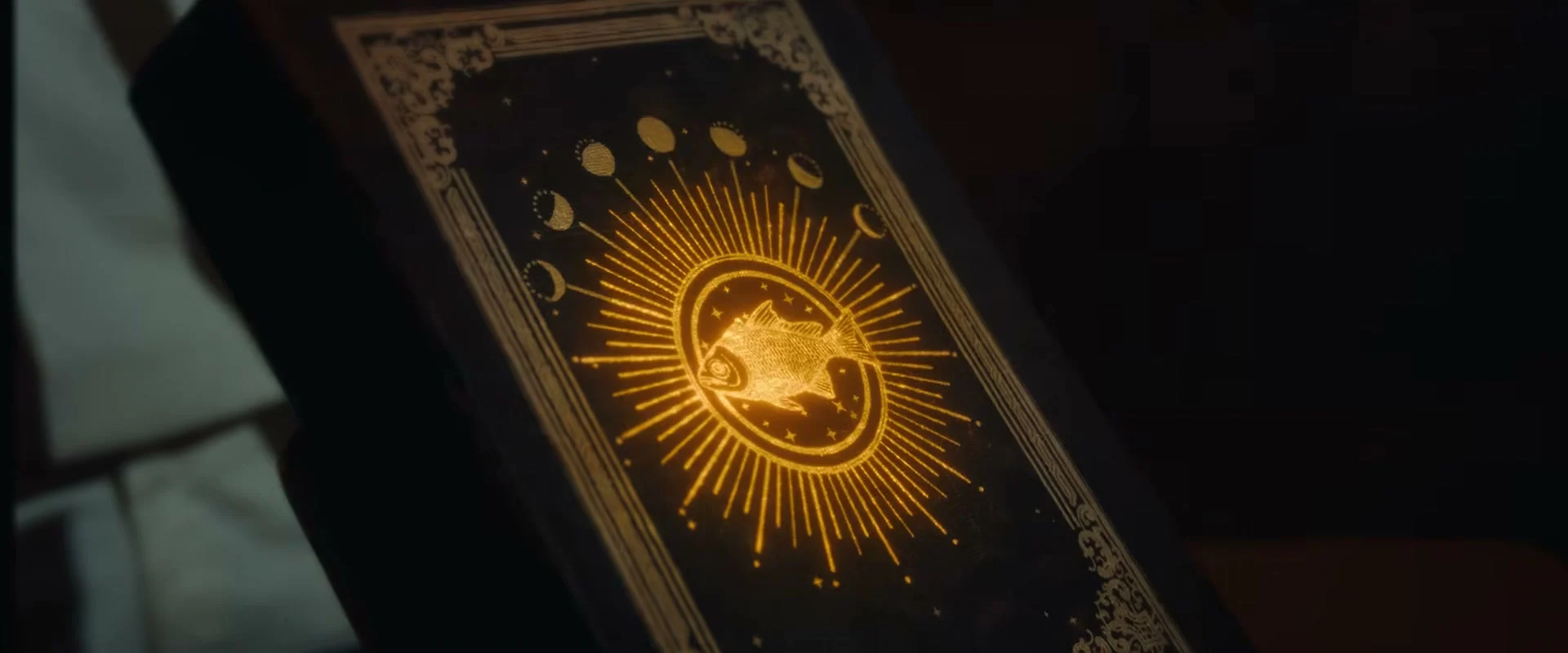 An ornate book with a golden circular fish ornament